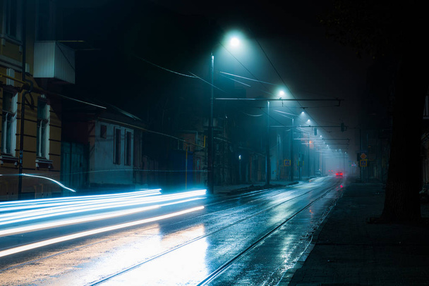 Luces de la calle nebulosa noche brumosa. Ruta del tranvía en una calle de la ciudad
 - Foto, imagen