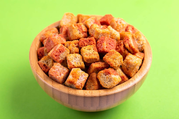 Bacon flavored crackers in wooden bowl on bright colored background. Beer appetizer. Cinema snack. Copy space - Zdjęcie, obraz