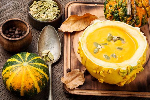 Vegetarian pumpkin cream soup with seeds in pumpkin.Seasonal autumn food - Fotoğraf, Görsel