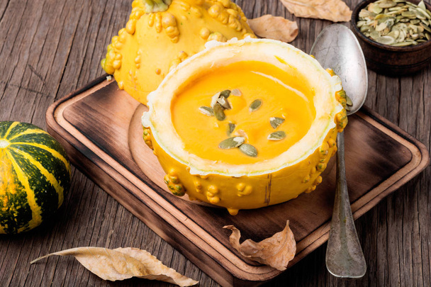 Vegetarian pumpkin cream soup with seeds in pumpkin.Seasonal autumn food.Cream soup in pumpkin - Fotoğraf, Görsel