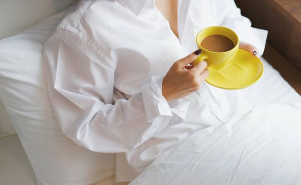  young woman lying in bed with cup of hot coffee in bedroom - Foto, Bild