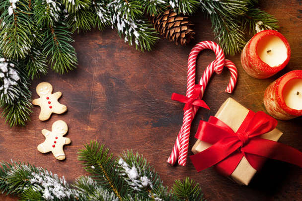Carte de Noël avec biscuits au pain d'épice, bougies et branche de sapin recouverte de neige sur fond bois. Vue de dessus avec espace pour vos salutations
 - Photo, image
