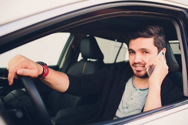 Shot of a handsome man using mobile phone while driving. - Foto, afbeelding