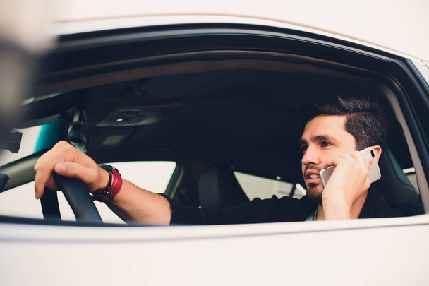 Shot of a handsome man using mobile phone while driving. - Fotó, kép