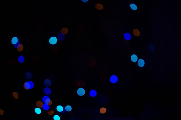 Beautiful bokeh on a dark background. Festive lights. Garland. Dark key. Picture under the background. - Photo, image