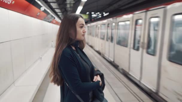 Młoda dziewczyna stoi na platformie i czeka w pociągu przyjechać - Materiał filmowy, wideo
