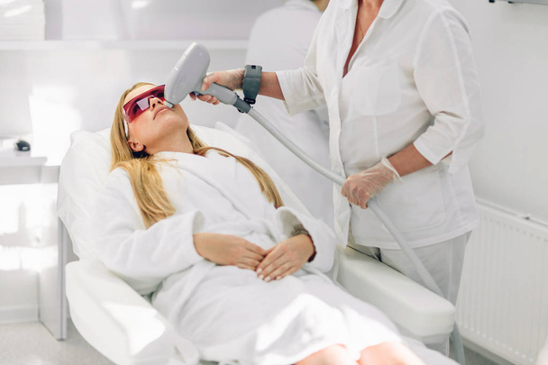 Woman getting laser and ultrasound face treatment in medical spa center - Foto, Bild