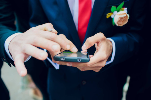 Bearded groom holding smartphone on wedding morning. - Photo, Image