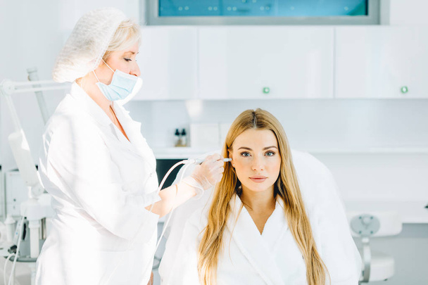 Blonde woman undergoes a procedure of facial gas-liquid oxygen peeling - Photo, Image