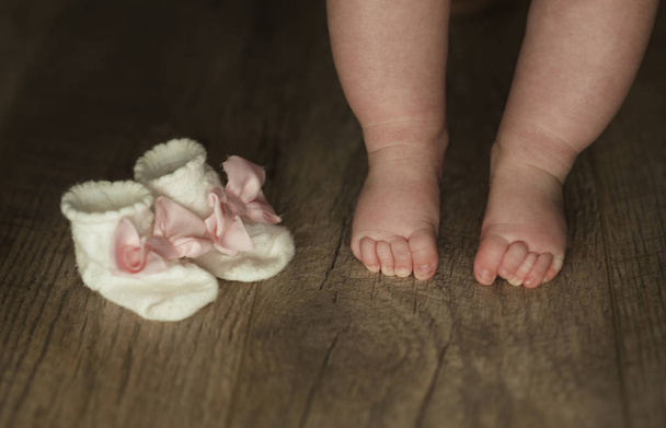 legs of newborn baby close up on wooden background - Foto, afbeelding