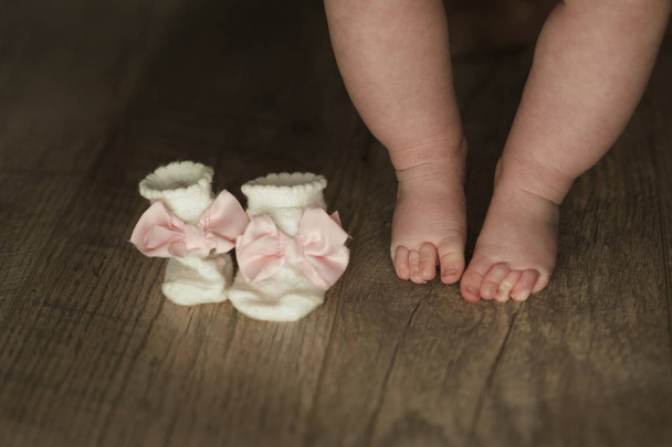 legs of newborn baby close up on wooden background - Foto, afbeelding