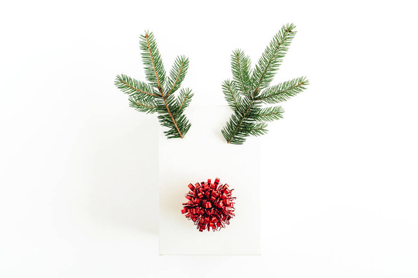 Christmas, New Year minimal concept. Christmas deer symbol made of gift box, fir branches and red bow isolated on white background. Flat lay, top view. - Photo, Image