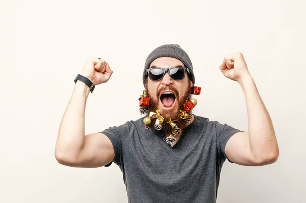 Homem animado com barba decorada na atmosfera de Natal celebrando o sucesso
 - Foto, Imagem