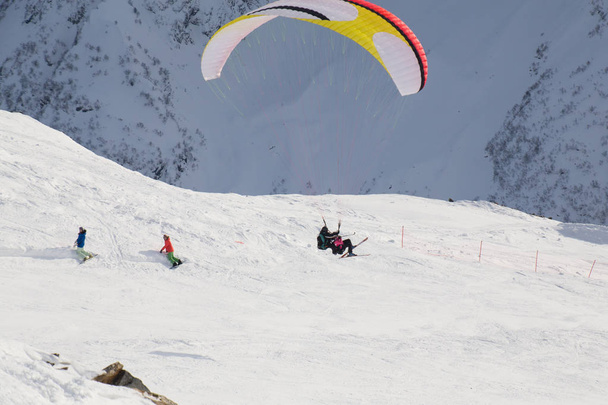 paraglider with two people - an instructor and a passenger flying the sky in the snowy mountains - Foto, imagen