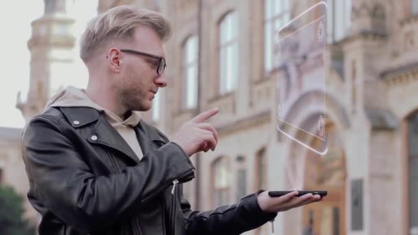 Έξυπνος νεαρός με γυαλιά δείχνει μια εννοιολογική ολόγραμμα μηχανικό ρολόι - Πλάνα, βίντεο