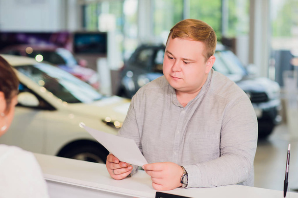 successful businessman in car dealership - sale of vehicles to customers - Foto, afbeelding