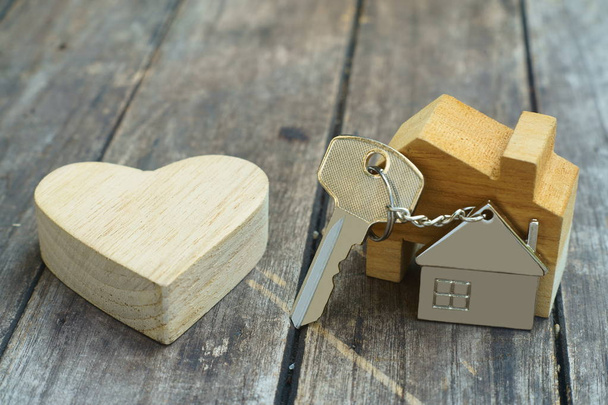 Chave em casa com chaveiro casa e coração de madeira zombar no fundo de madeira vintage, casa conceito doce casa
 - Foto, Imagem