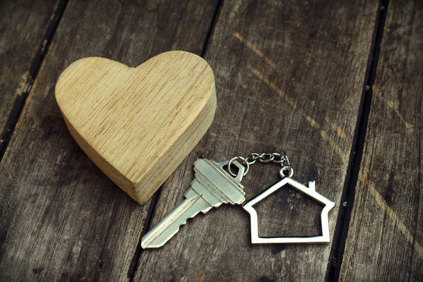 Home key with house keychain and wooden heart mock up on vintage wood background, home sweet home concept - Photo, Image