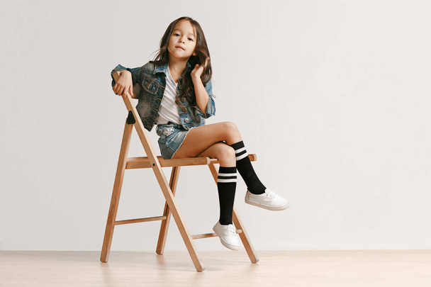 Full length portrait of cute little kid in stylish jeans clothes looking at camera and smiling - 写真・画像