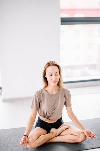 young fit woman with closed eyes sitting in yoga position - Fotoğraf, Görsel