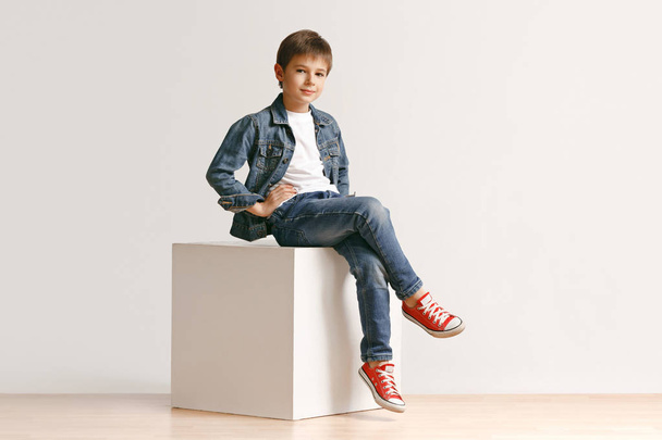 The portrait of cute little boy in stylish jeans clothes looking at camera at studio - Fotografie, Obrázek