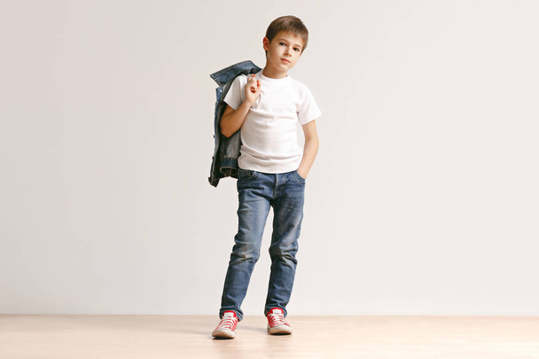The portrait of cute little boy in stylish jeans clothes looking at camera at studio - Foto, Bild