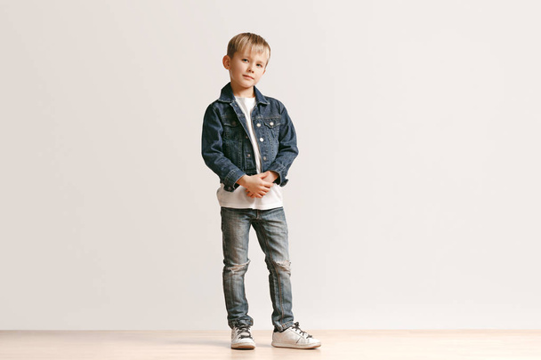 The portrait of cute little boy in stylish jeans clothes looking at camera at studio - Foto, imagen