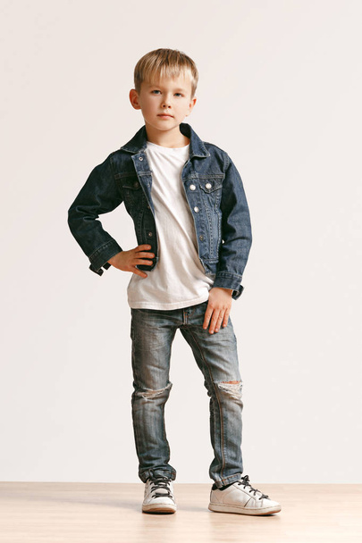 The portrait of cute little boy in stylish jeans clothes looking at camera at studio - Zdjęcie, obraz