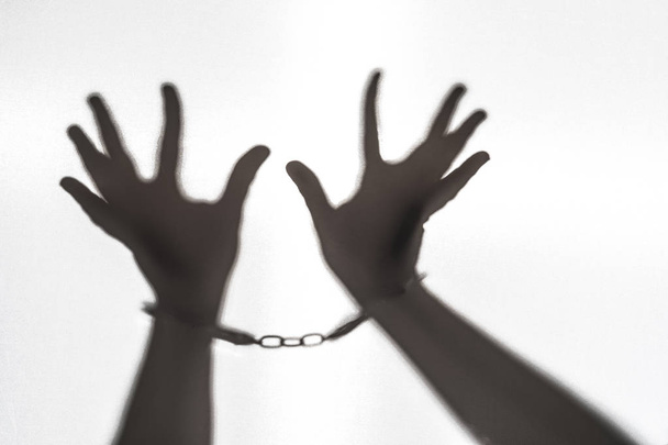 ヘルプでは、囚人の手。白い背景に手錠で手のシルエット - 写真・画像