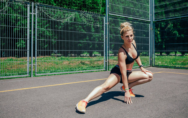 Sportswoman doing leg stretches - Фото, изображение