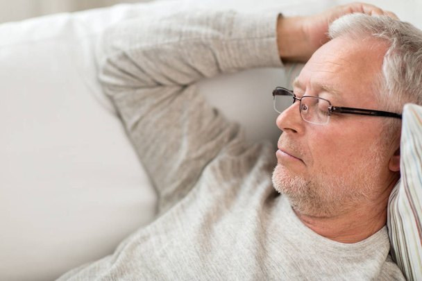 senior man sleeping on sofa at home - Photo, image
