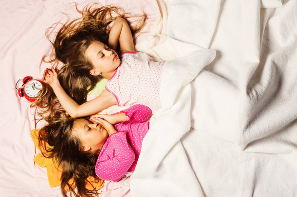 Kids in pink pajamas covered with white blanket - Фото, зображення