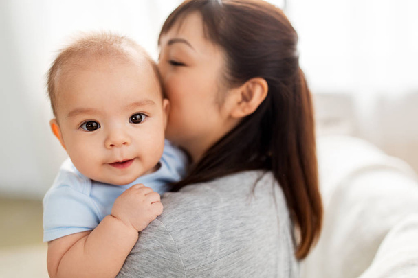 close up of happy mother kissing baby son at home - Photo, Image