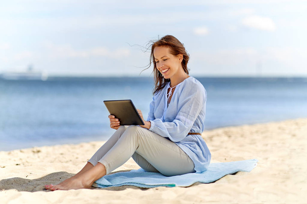 happy smiling woman with tablet pc on summer beach - 写真・画像