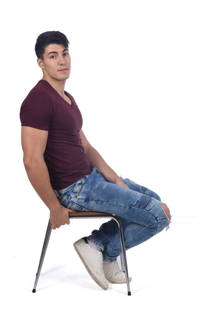 Young man sitting on a chair isolated on white - 写真・画像