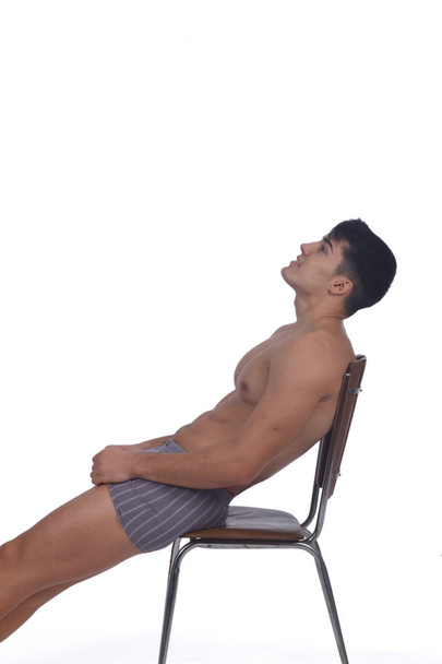 Young man naked and relaxed  sitting on a chair - Foto, immagini