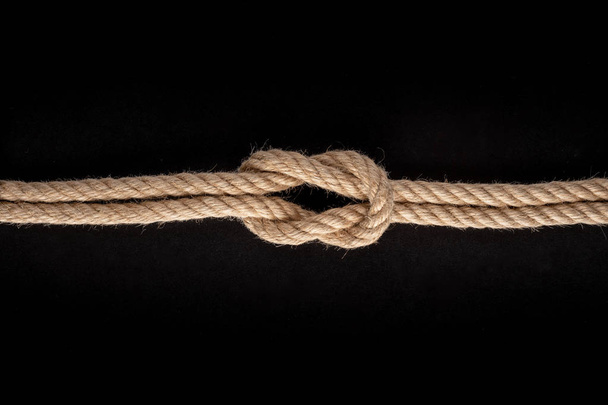 Square knot. Nautical rope knot on black background - Photo, image