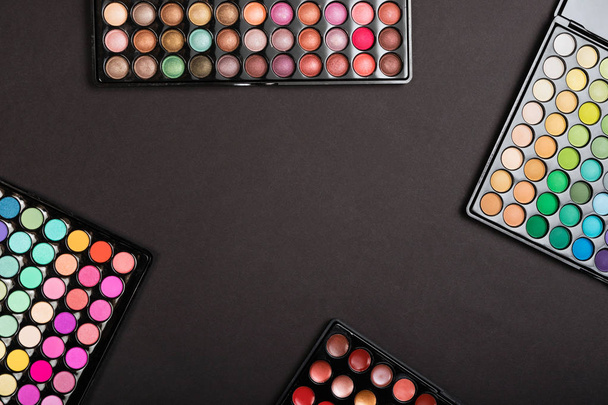 Layout of colorful make-up palettes on black background - Photo, image