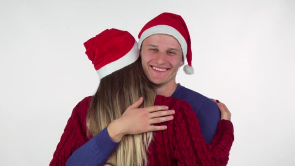 Handsome young man wearing Christmas hat hugging his girlfriend - Felvétel, videó
