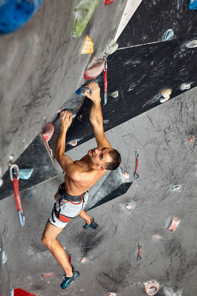 Male professional climber at indoor workout at bouldering centre. - 写真・画像