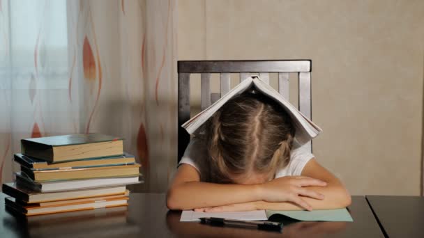Unavený školačka s knihami u stolu - Záběry, video