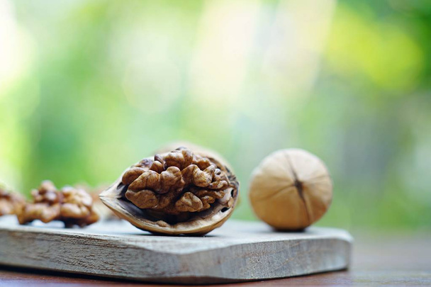 Group of walnuts and a crack nut in wooden bowl on wood background, copy space, super food concept - Zdjęcie, obraz