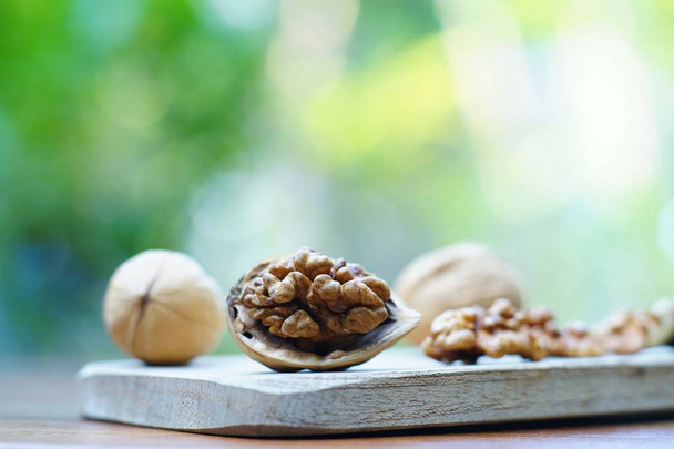 Group of walnuts and a crack nut in wooden bowl on wood background, copy space, super food concept - Photo, image