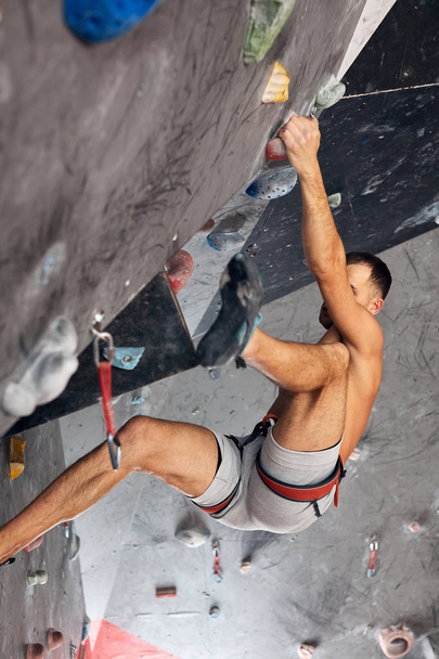 Male professional climber at indoor workout at bouldering centre. - 写真・画像