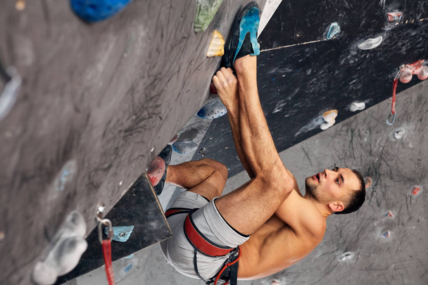 Male professional climber at indoor workout at bouldering centre. - Photo, image