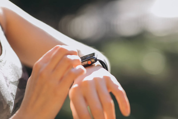 Woman using her smartwatch touchscreen wearable technology device in morning lights - 写真・画像