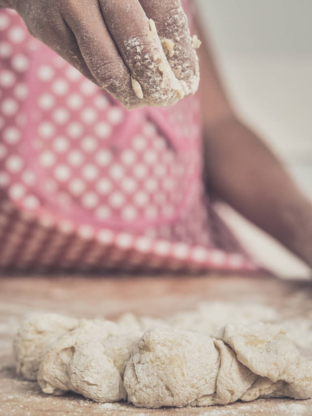 Girl hands sprinkle flour powder on dough. - Foto, Imagen