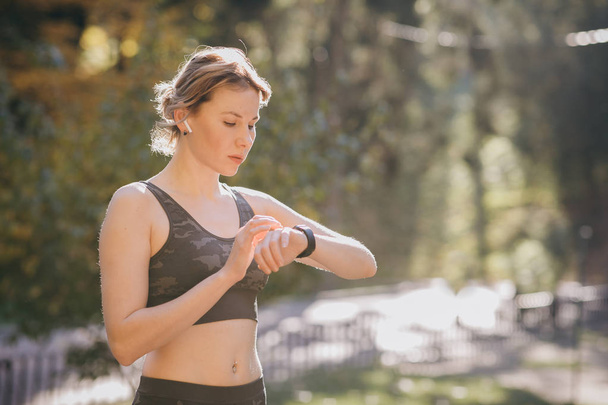 Woman using her smartwatch touchscreen wearable technology device in morning lights - 写真・画像