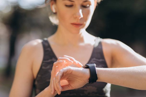 Woman using her smartwatch touchscreen wearable technology device in morning lights - Foto, immagini