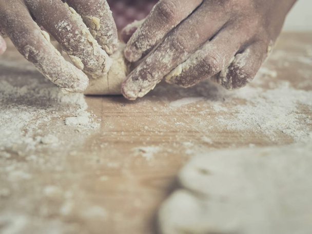 Girl hands are rolling a croissant from dough on wooden board. - Foto, Imagen
